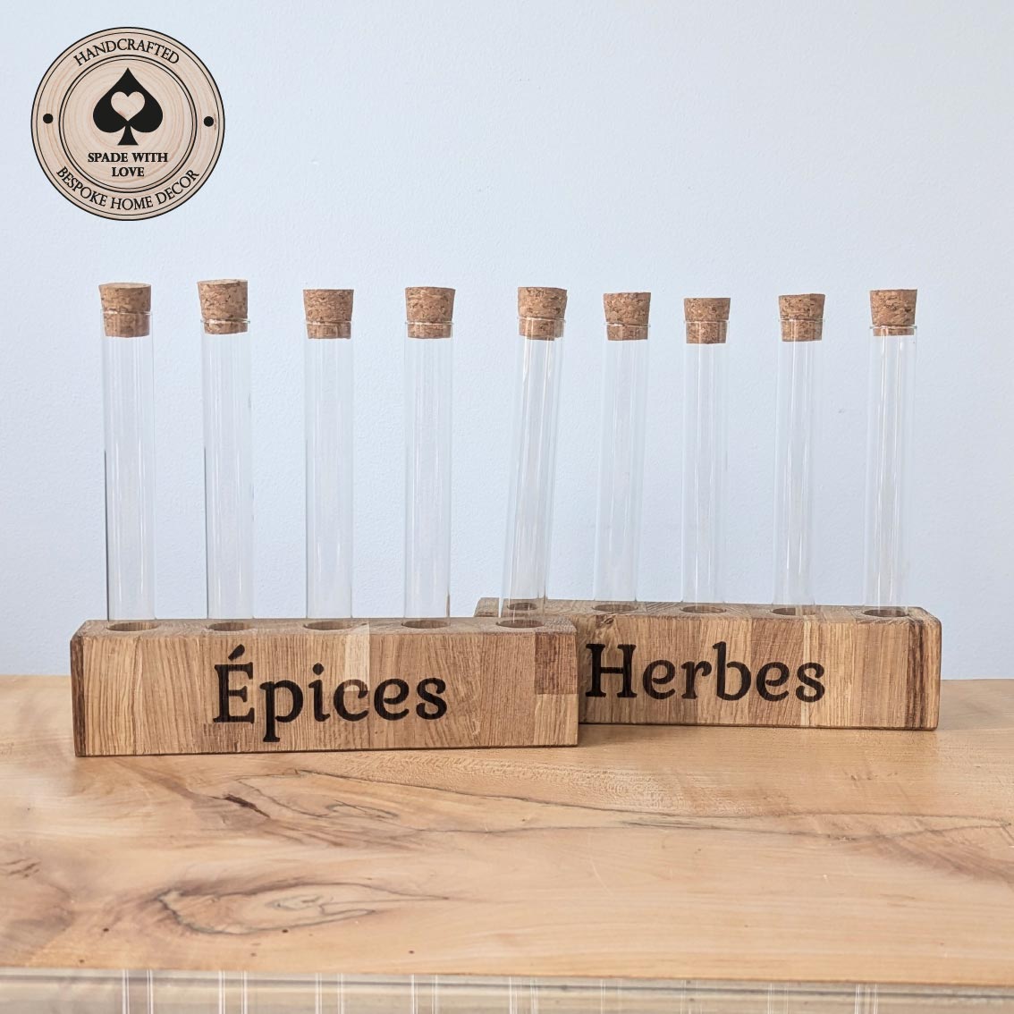 Wooden spice rack with glass jars labeled 'Epices' and 'Herbes' on a light blue background.
