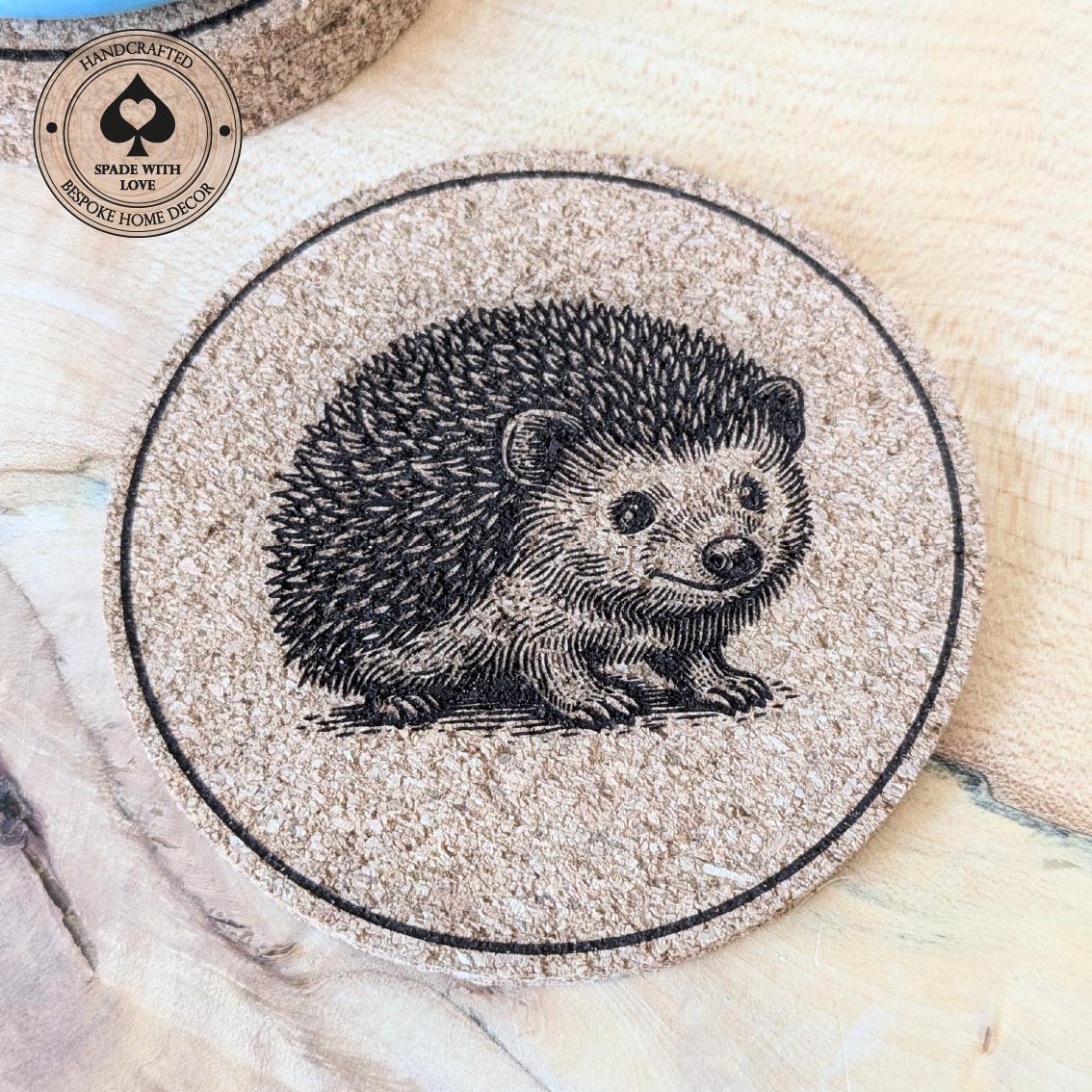 Round cork coaster with a hedgehog design on a wooden surface