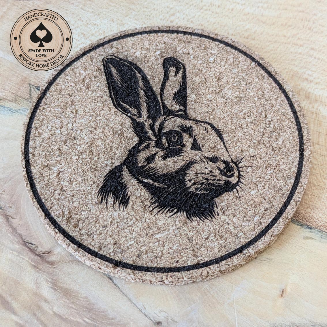 Round cork coaster with rabbit illustration on a wooden Surface